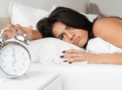 Image of dissatisfied woman 20s lying in bed on pillow, and turn